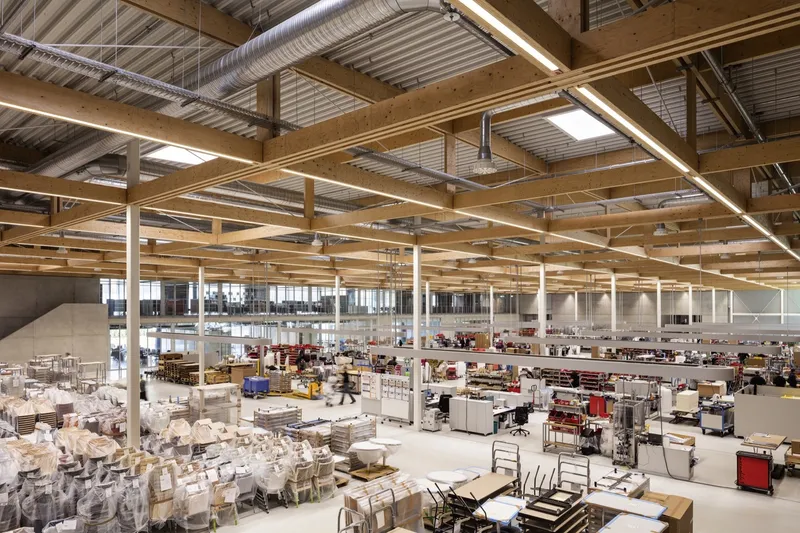 Wide view of the production floor with exposed timber structure, corrugated metal ceiling and active workstations
