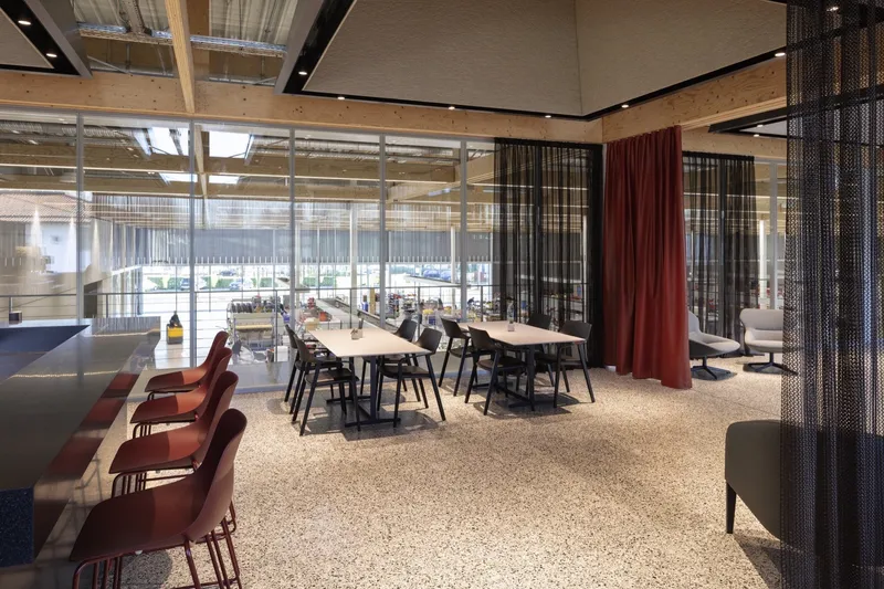 Communal workspace with terrazzo flooring and colored curtain dividers beneath clerestory windows