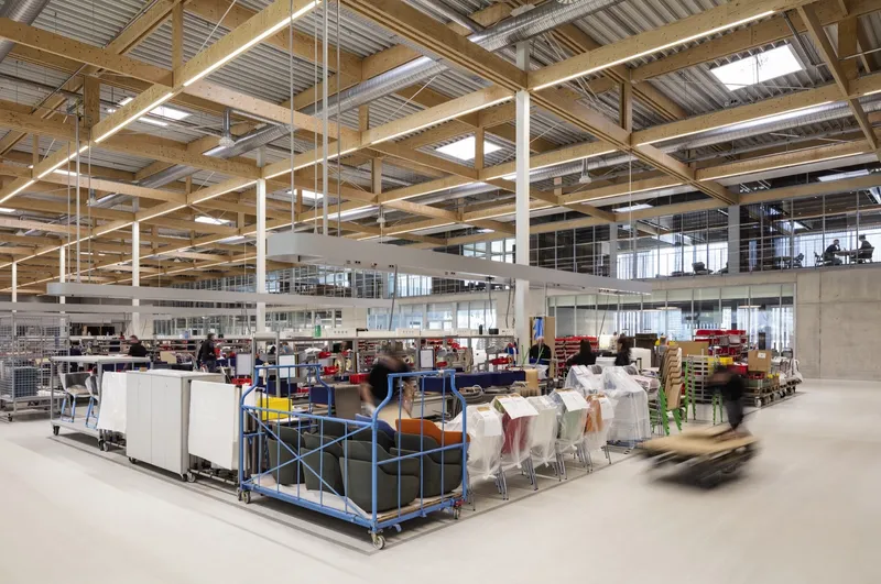 Warehouse floor with exposed timber beams and corrugated metal ceiling over work stations and carts