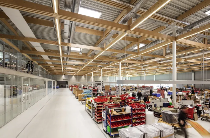 Interior view along elevated walkway overlooking warehouse space with timber grid structure above