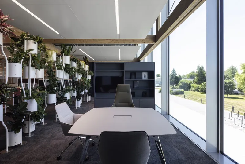 Conference room with floor-to-ceiling glazing overlooking a green lawn and vertical planters on the interior wall