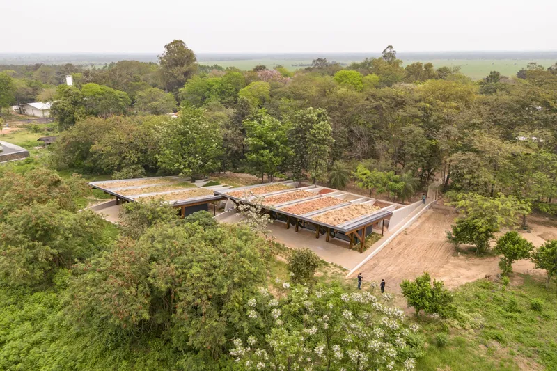 Aerial view of two low-slung pavilions with wide overhanging roofs nestled among dense green trees