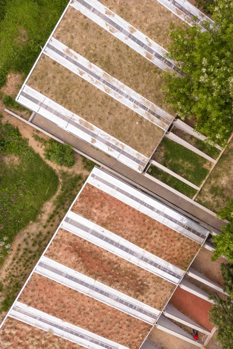Aerial view of two angled rooftops with solar panel arrays and planted green roof sections