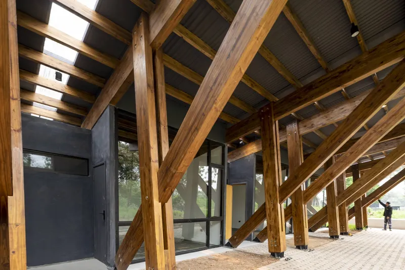 Covered walkway with exposed timber frame, metal roofing and glass doors leading to interior spaces
