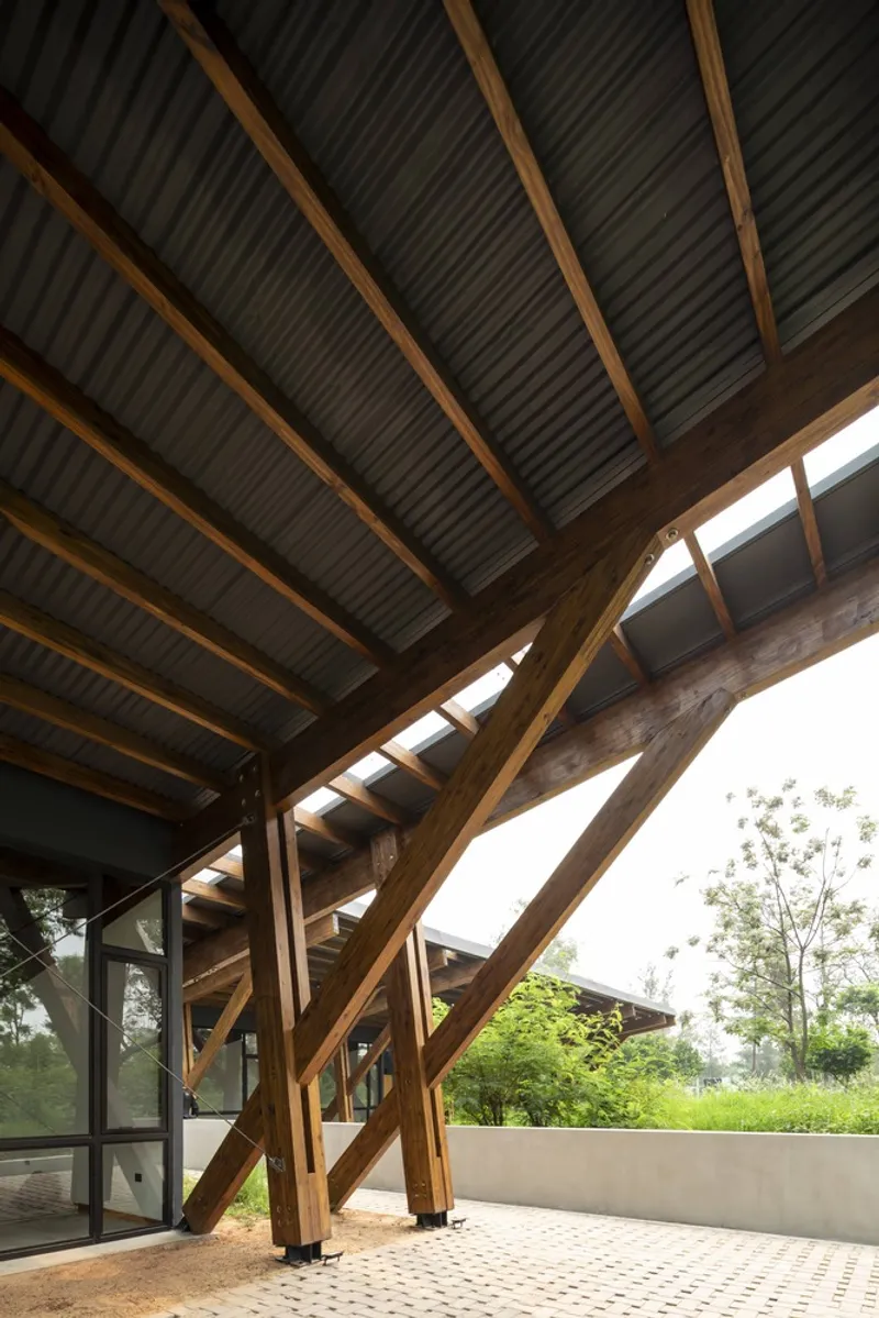 Covered terrace with diagonal timber bracing supporting corrugated metal ceiling and perforated concrete floor