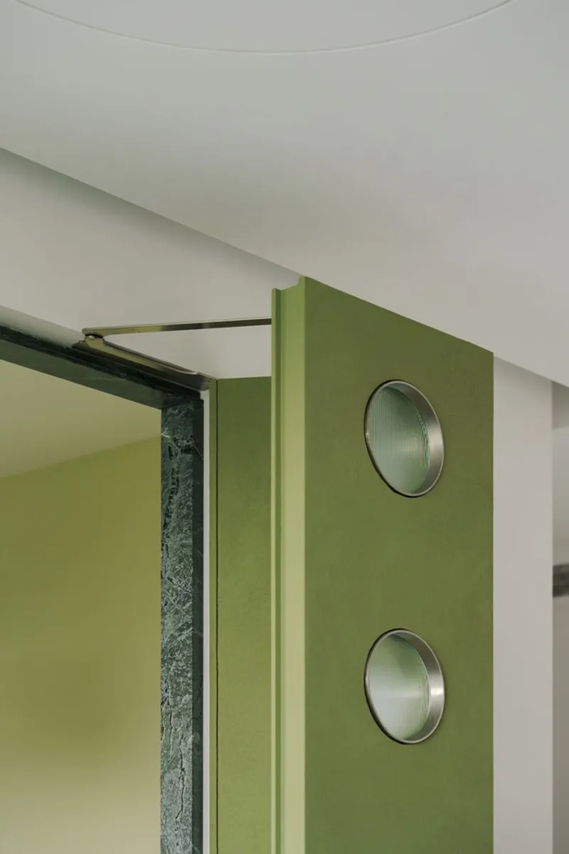 Detail of green wall panel with two circular metal insets and sliding track hardware
