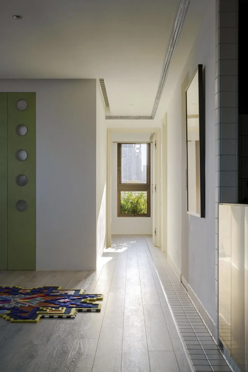 Hallway with skylight above pale wood flooring leading to window overlooking greenery and towers