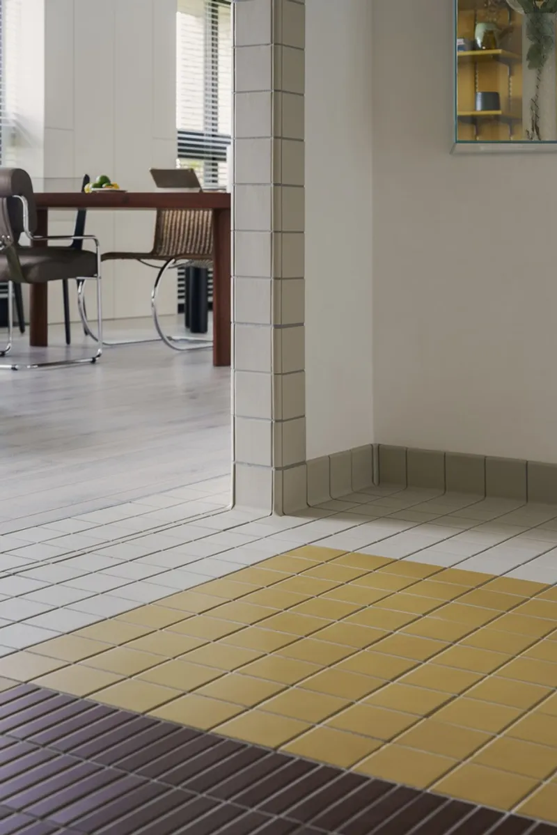 Tiled floor threshold in yellow, grey and violet tones beneath white wall and column