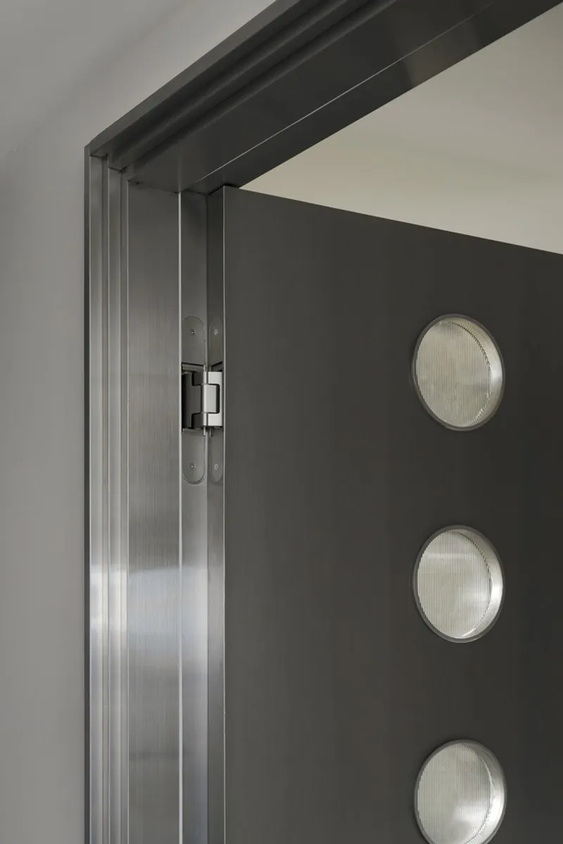 Dark door with three circular reeded glass porthole windows and brushed steel frame
