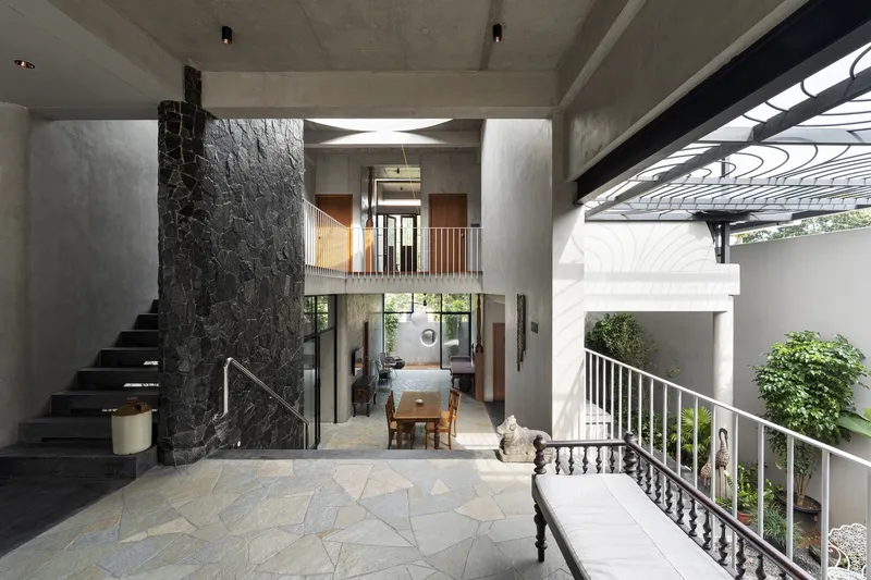 Multi-level interior atrium with exposed concrete ceiling, dark stone feature wall and central floating bridge