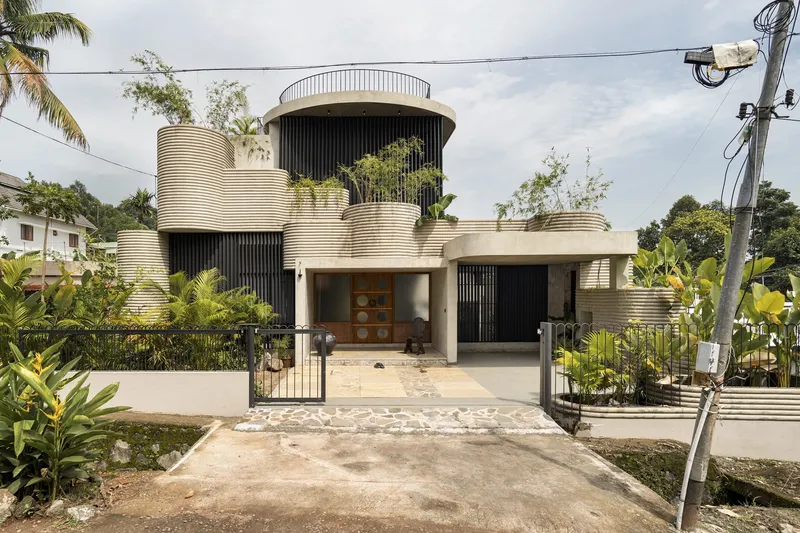Street view of the ribbed cylindrical volumes with planted terraces and tropical foliage