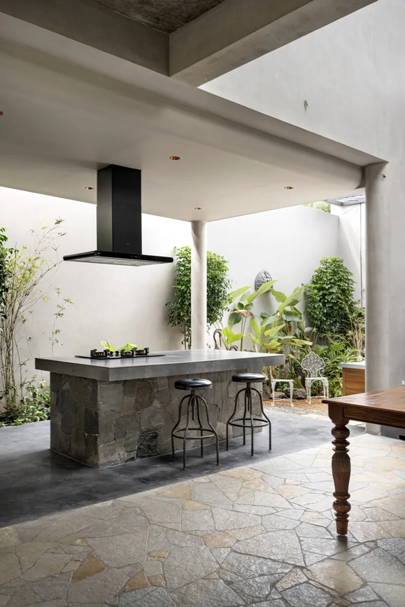 Kitchen island with black range hood opening to a planted courtyard with climbing vines