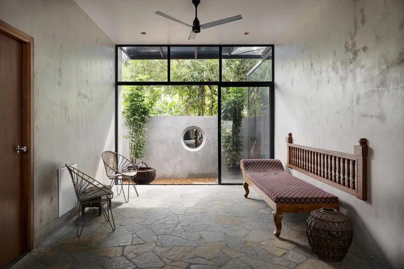Interior room with steel-framed windows overlooking a walled courtyard with circular aperture