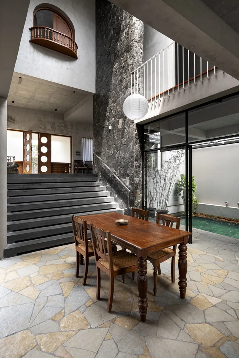 Double-height space with marble-clad column and stone staircase beneath a concrete ceiling