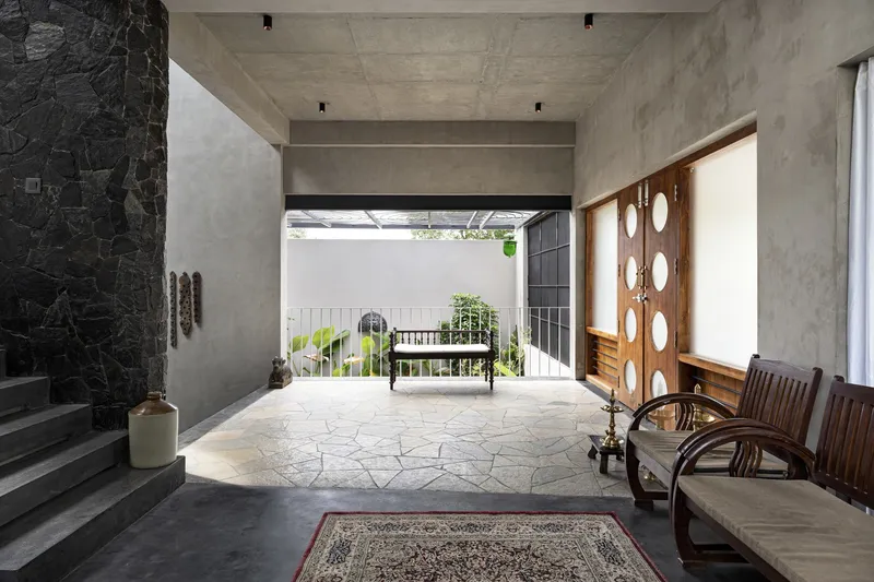 Ground-floor entry hall with stone-paved floor opening to a planted courtyard beyond the railing