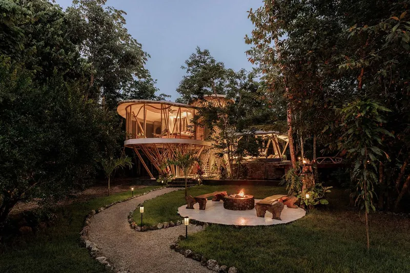 Garden view of the elevated bamboo structure with central fire pit at dusk