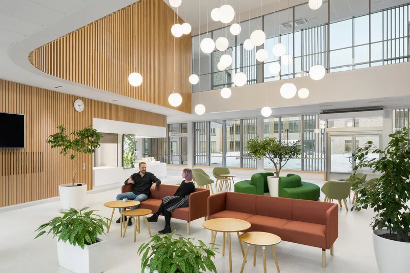 Double-height lobby with clustered globe pendants, slatted wood ceiling, and glazed mezzanine overlooking courtyard
