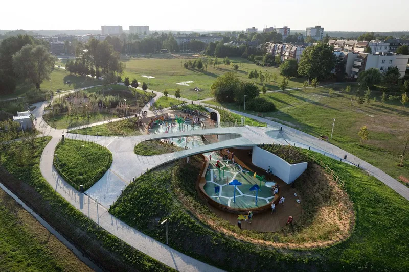 Aerial view of the curving rooftop canopy sheltering playground zones carved into circular planted berms