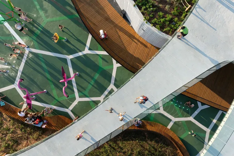 Top-down view of the curved timber deck wrapping the green hexagonal patterned splash zone