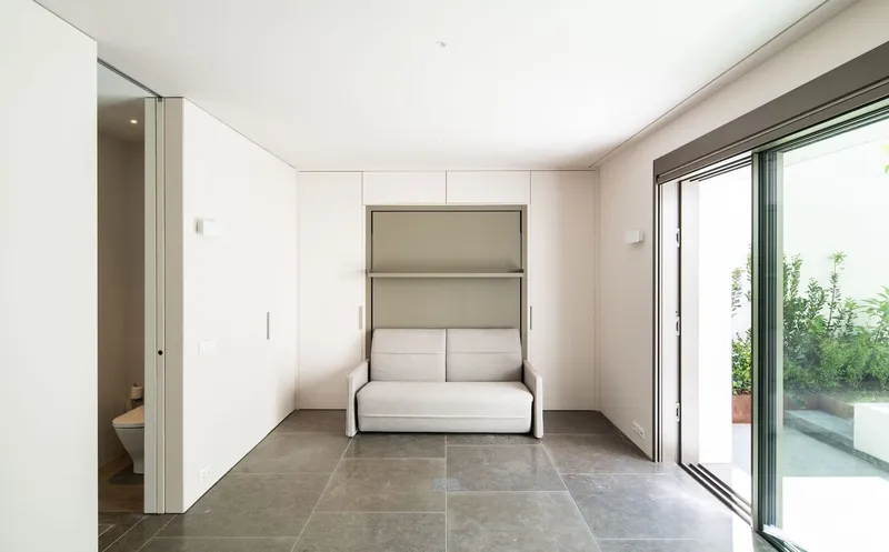 Interior room with fold-down wall bed and grey stone floor opening to a terrace