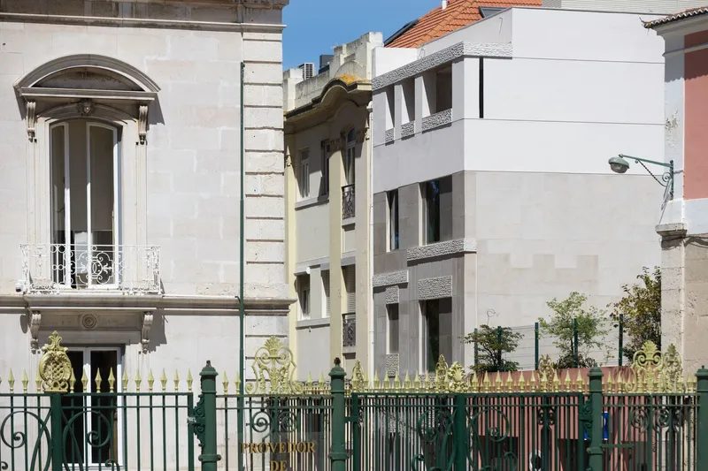 Streetscape view showing the textured facade amid a row of historic buildings and ornamental fencing