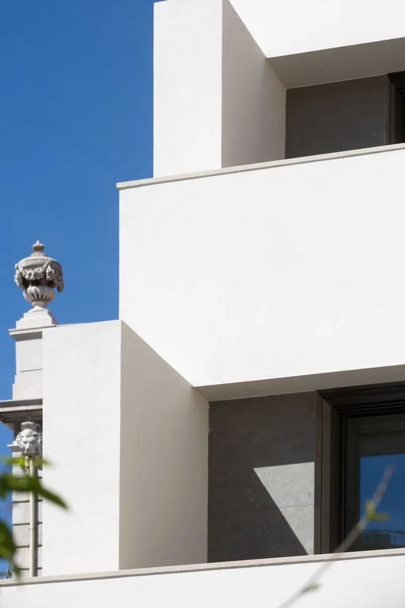 White stucco balconies stepping back against clear blue sky with ornamental urn visible