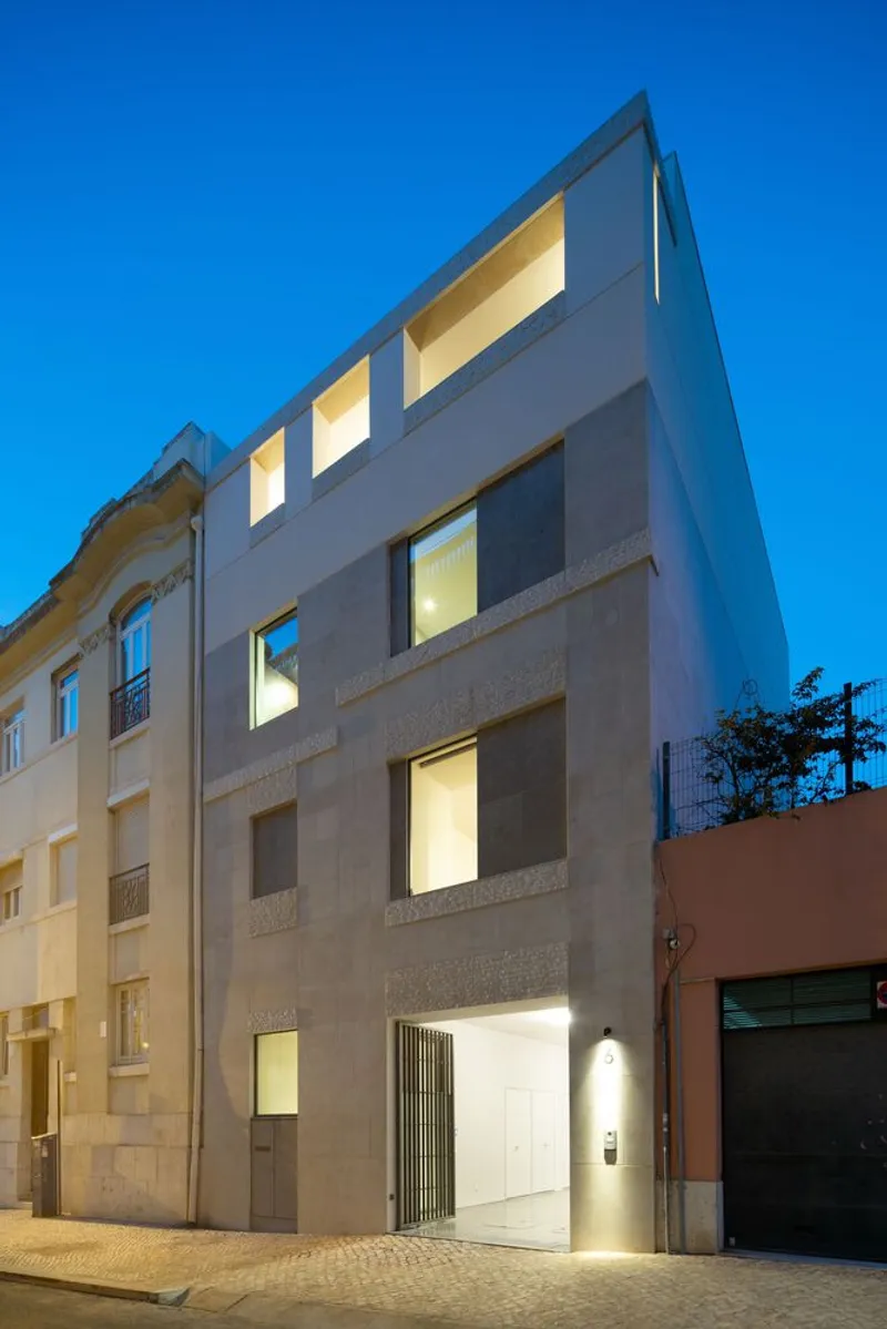 Street facade with recessed window openings and illuminated interiors at twilight