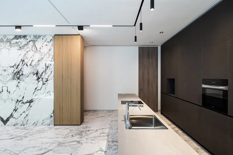 Kitchen island with integrated sink and timber batten screen next to veined marble cladding
