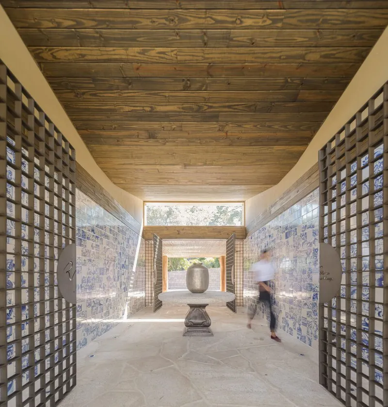 Corridor with timber lattice screens flanking blue-patterned tile walls and a wood plank ceiling