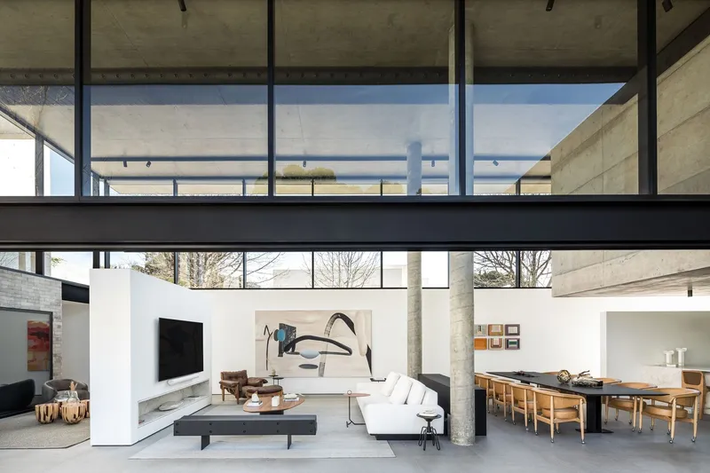 Double-height living space with concrete columns and clerestory windows framing bare trees outside