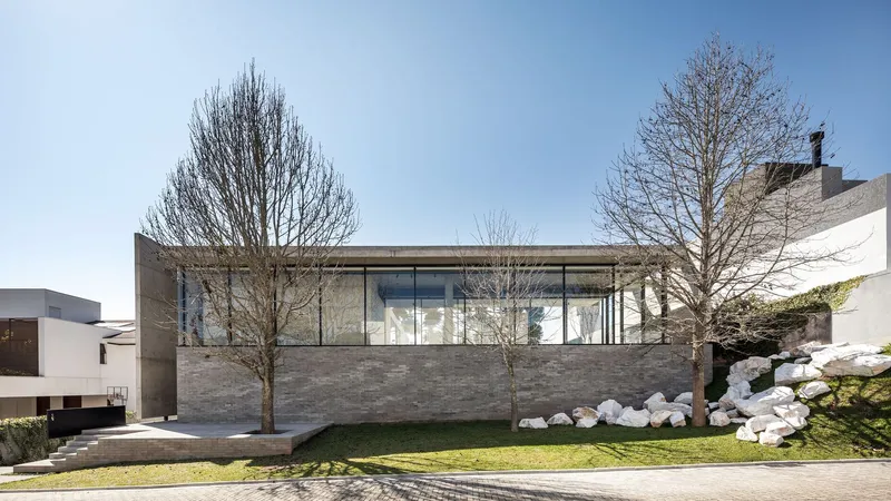 Front elevation showing horizontal brick plinth below continuous glazing under a flat concrete roof