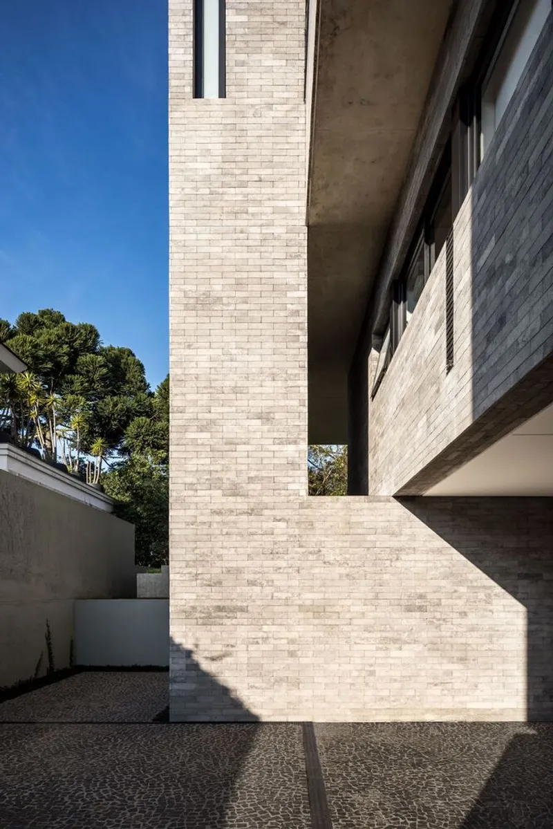 Detail of brick-clad structural column supporting cantilevered concrete soffit under clear blue sky