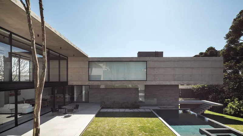 Rear courtyard with concrete volumes around a lawn terrace and pool edge in bright daylight
