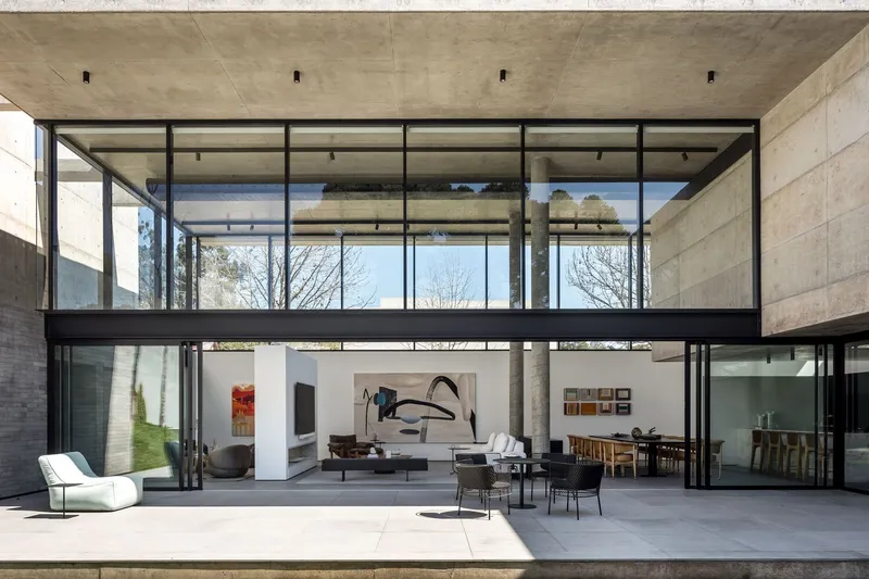 Open-air living room beneath cantilevered concrete floor with steel-framed glazing on three sides