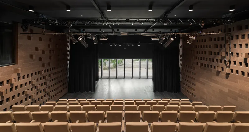 View from stage toward glass doors with black curtains and cork acoustic walls in the theatre