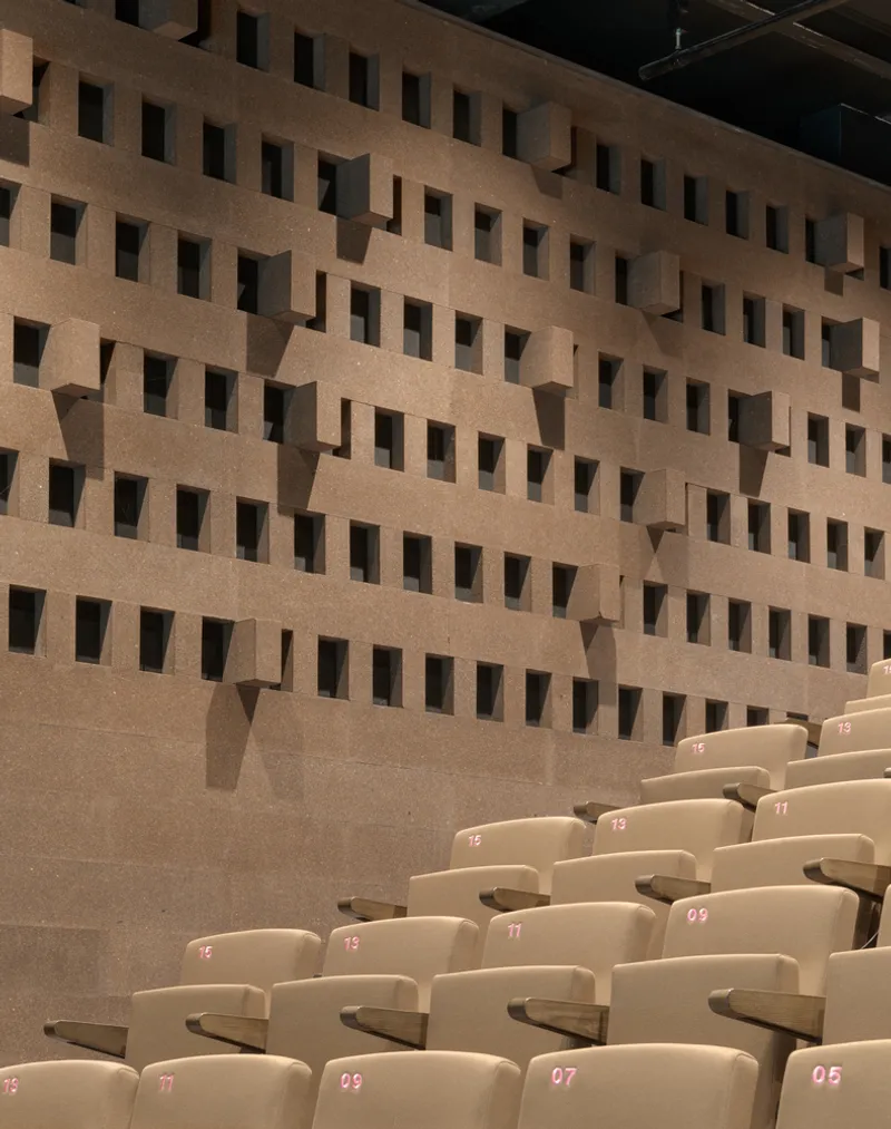 Angled view of numbered theatre seats below the textured cork acoustic wall with protruding blocks