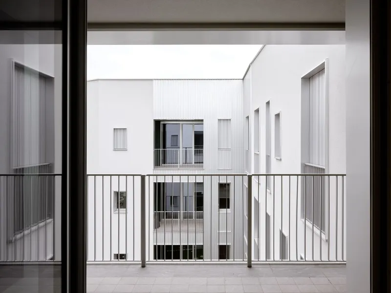 View through a balcony railing toward the interior courtyard facades with varied window placements