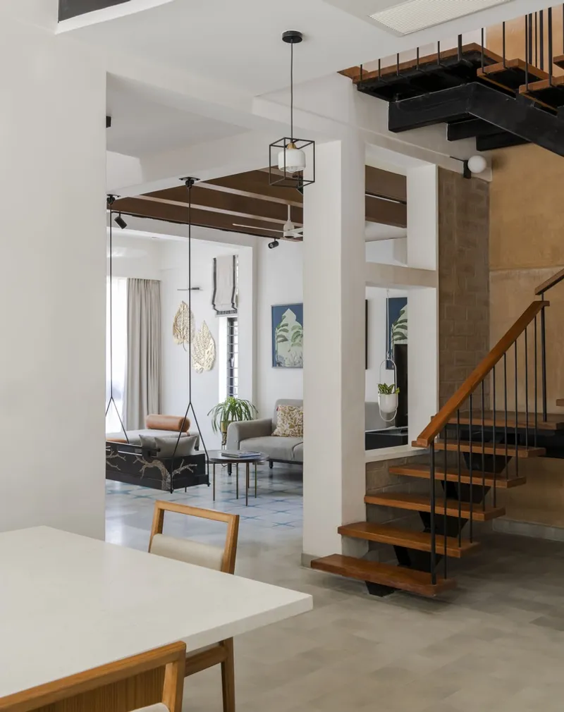 Open-plan living area with exposed staircase and suspended swing chair under a monkey bar