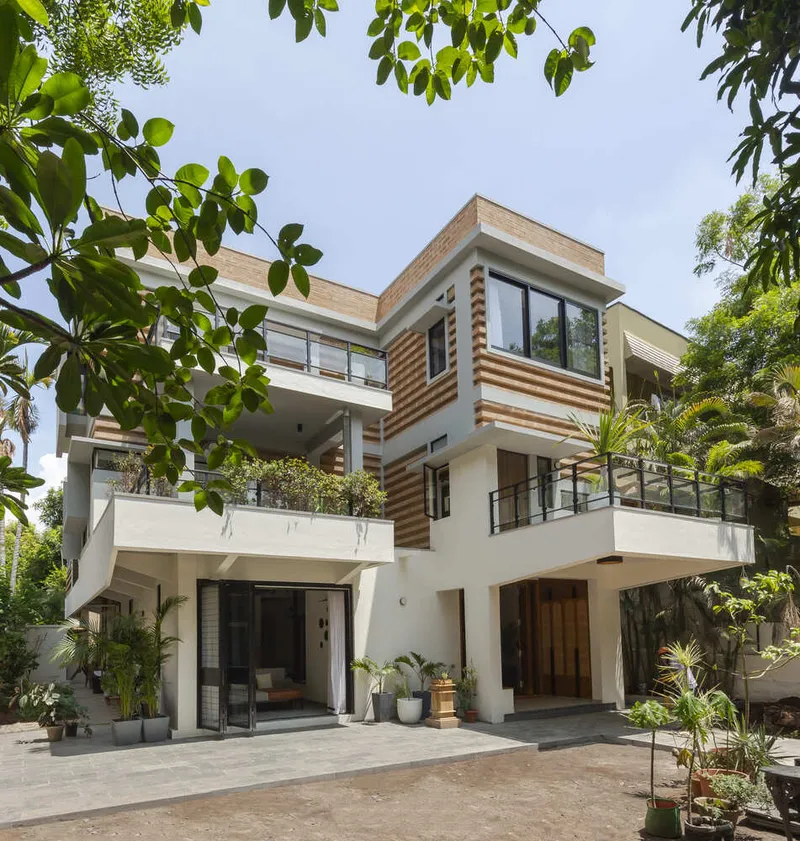 Entry courtyard with planted terraces and glass doors beneath cantilevered balconies with metal railings