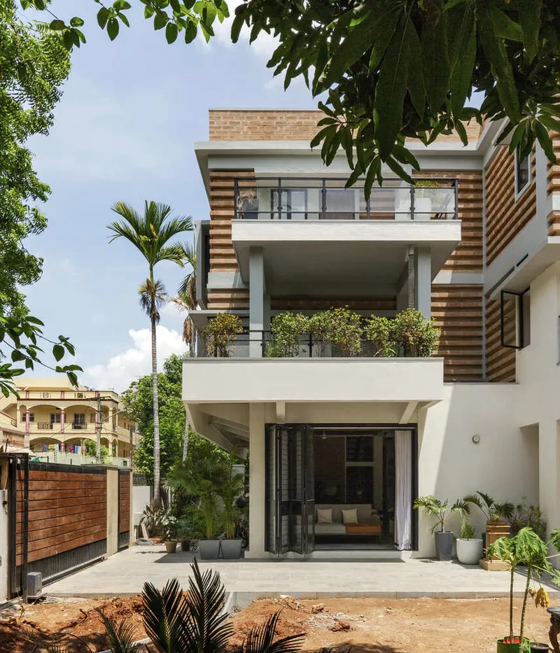 Street facade with alternating white stucco and horizontal wood cladding panels beneath palm trees