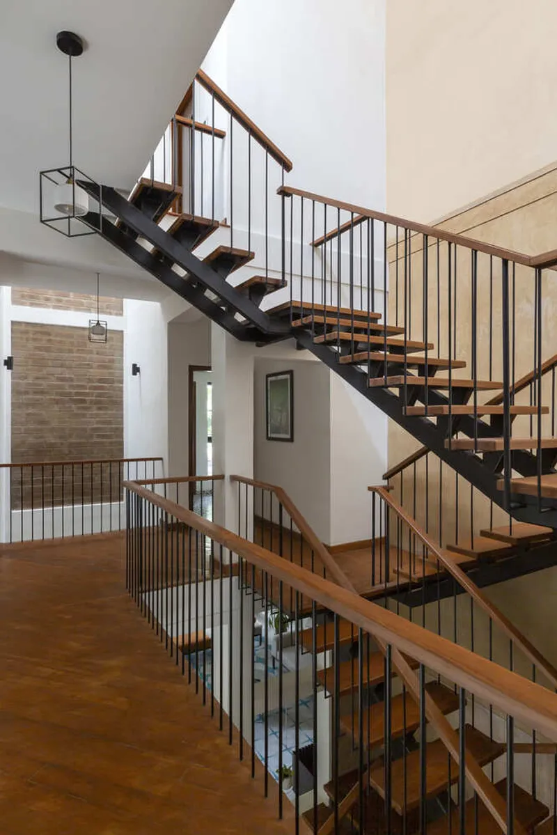 Floating staircase with open timber treads and black steel stringers spanning across a double-height void