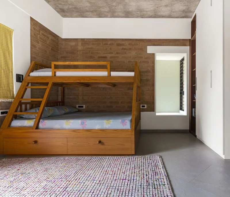 Timber bunk bed with storage drawers against exposed brick walls in a room with polished concrete floor