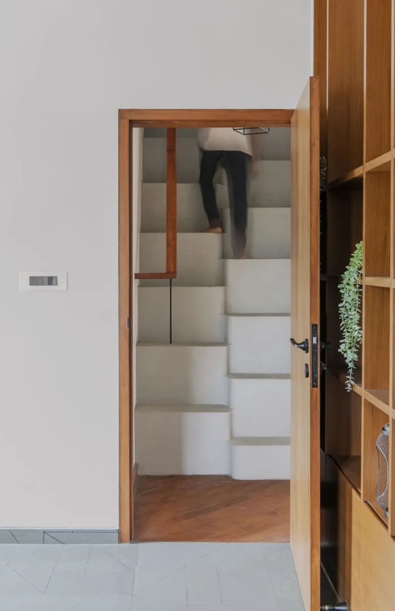 Timber-framed doorway opening to a concrete staircase with a person ascending the steps