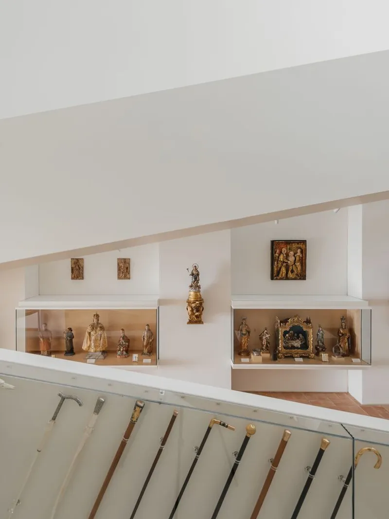 White display cases with religious artifacts arranged along an angled gallery wall