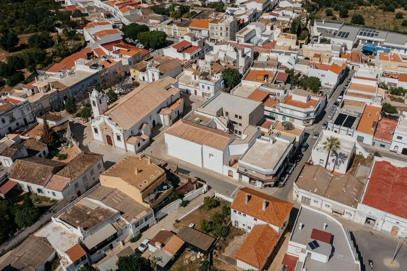 Aerial view of terracotta rooftops and white volumes densely clustered in a town center
