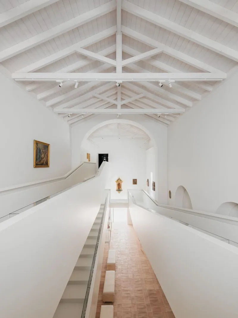Interior view of the vaulted gallery space with exposed timber trusses and terra cotta tile floor below