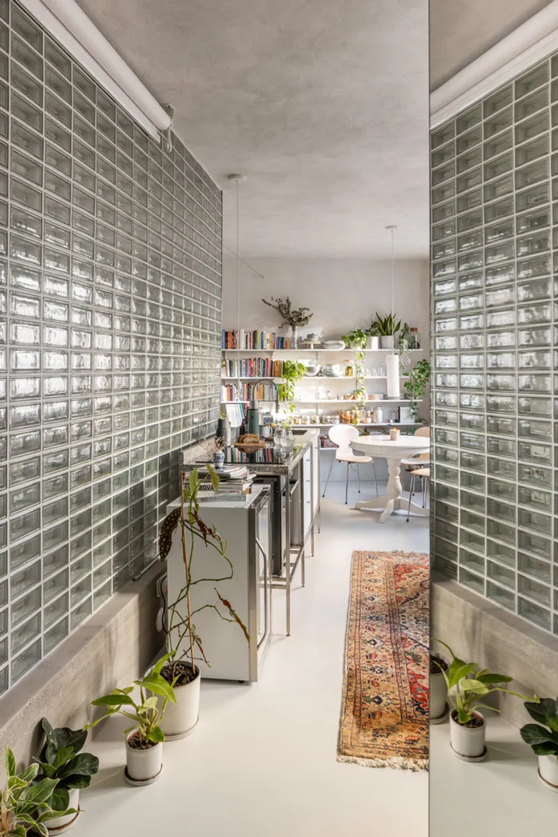 Corridor with glass block walls on both sides and potted plants along the concrete base