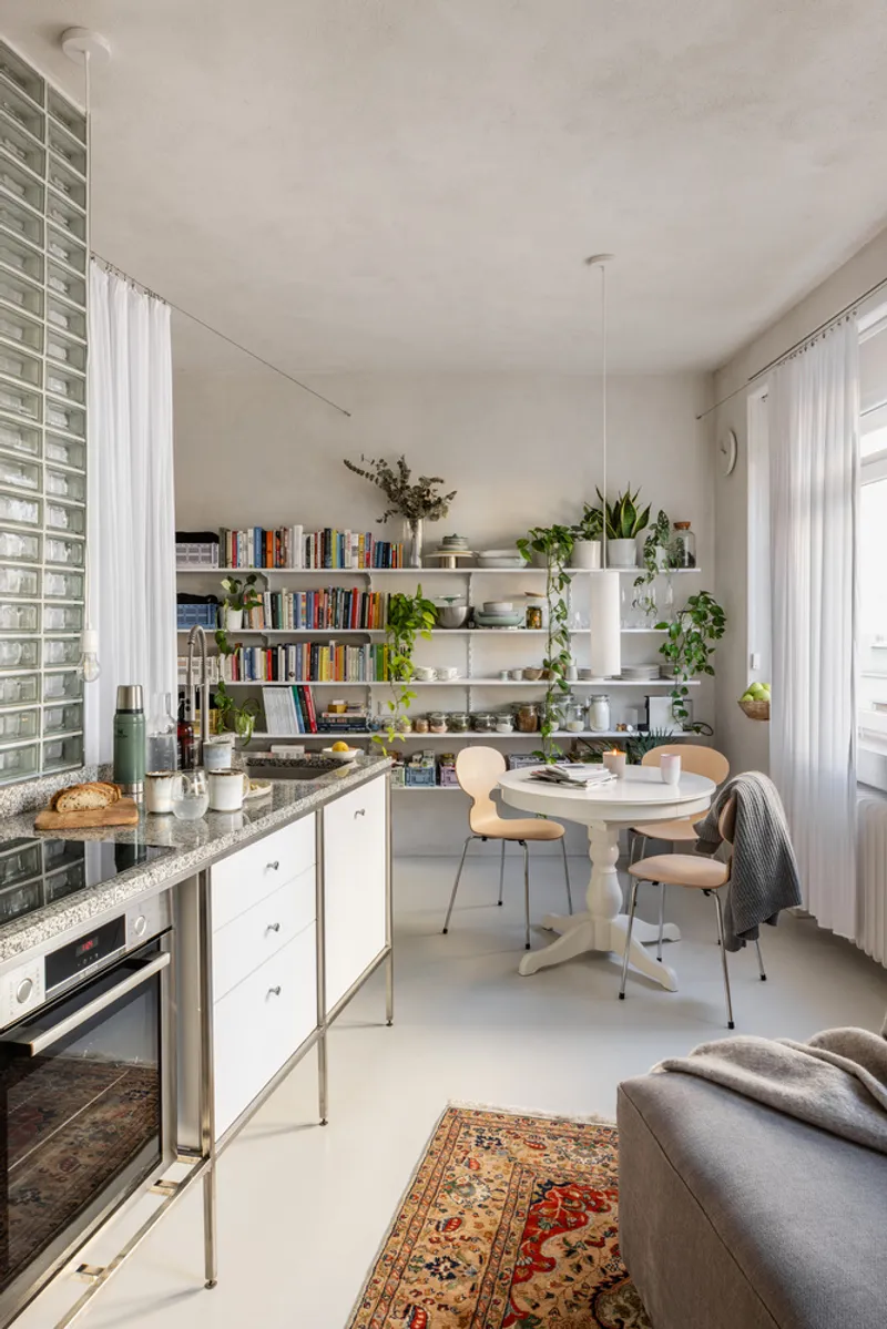 Kitchen and dining area with glass block wall, white shelving, and terrazzo countertop