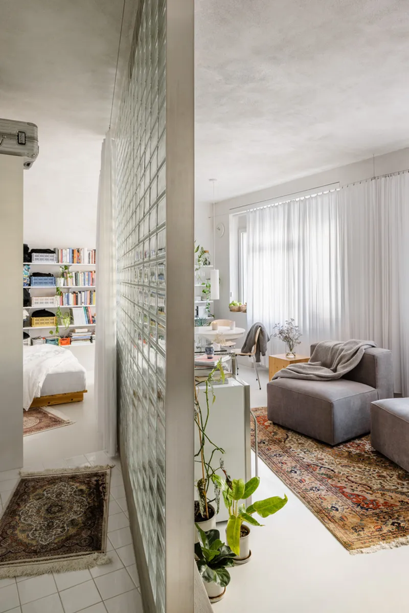 Translucent glass block wall separating the living room from the bedroom with potted plants at its base