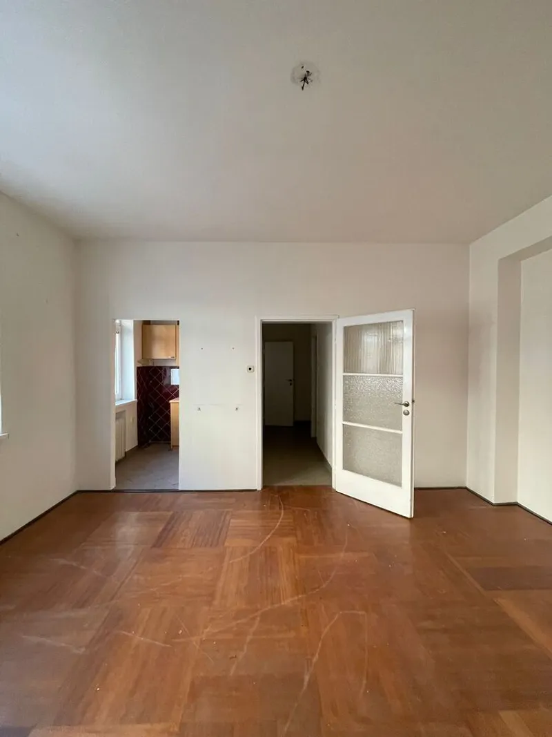 Empty room with herringbone parquet flooring and three doorways leading to adjacent spaces